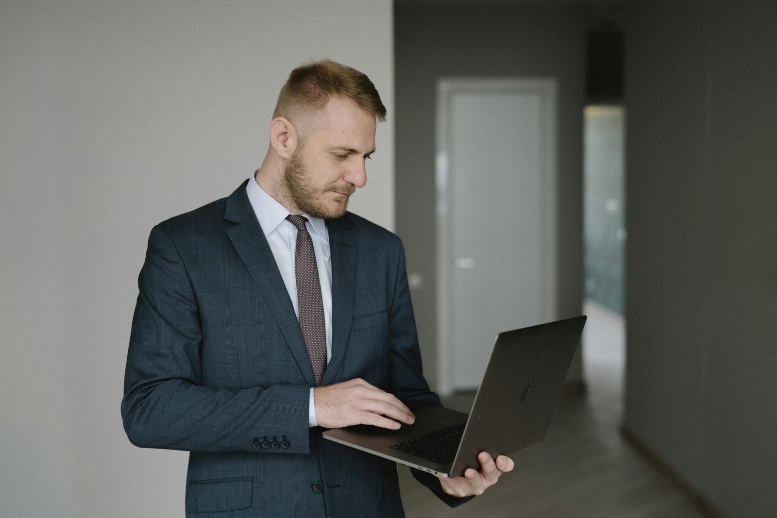 Businessman in suit works on laptop in a modern office setting, conveying professionalism.